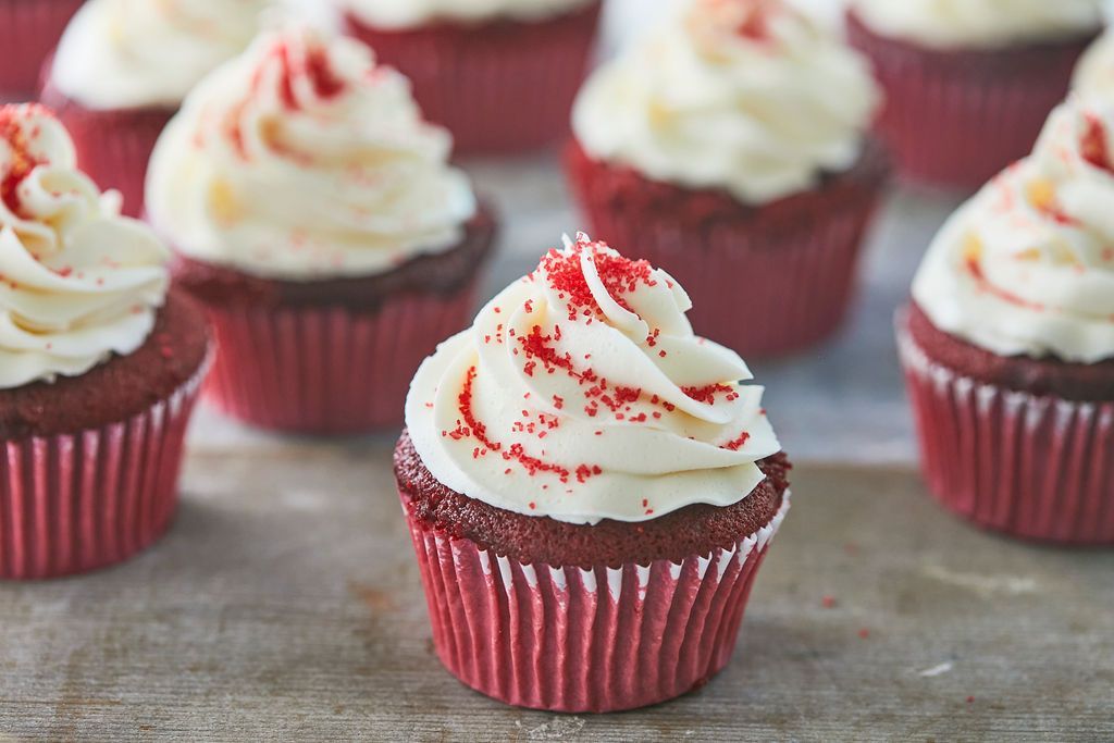 Batch of red velvet cupcakes swirled with cream cheese frosting