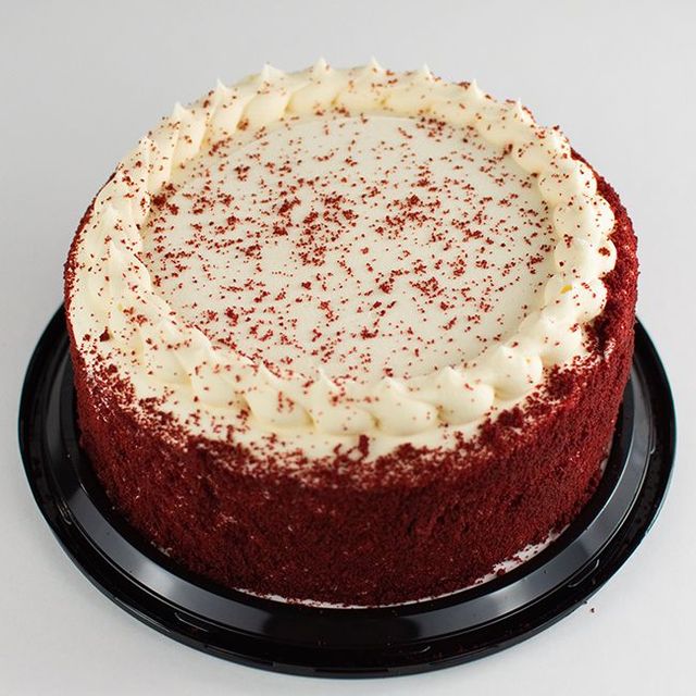Round two-layer red velvet cake with cream cheese frosting, finished with a smooth swirl on top